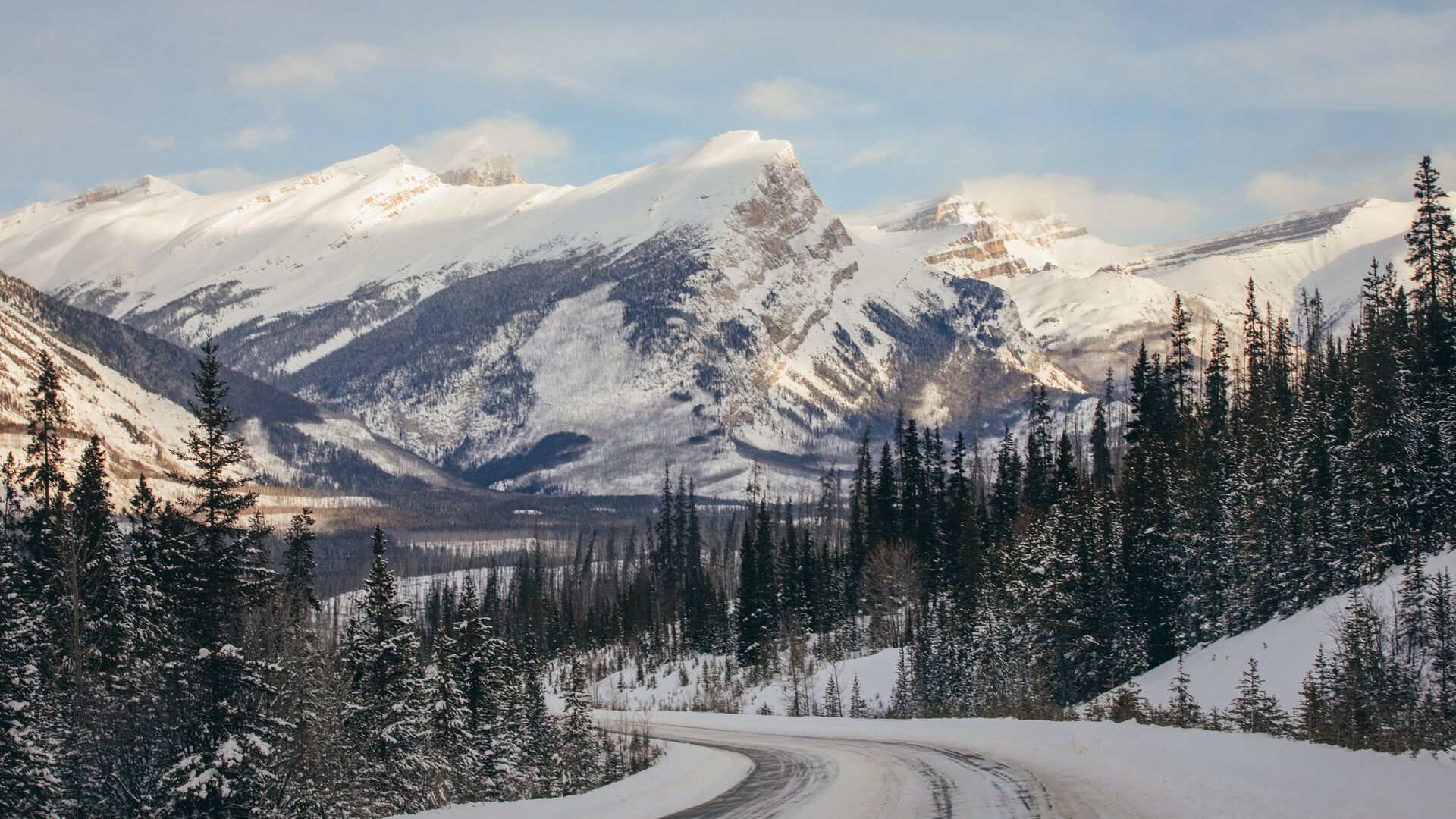 A road leading to snowcapped mountains on the way to icefield parkway in Canada.