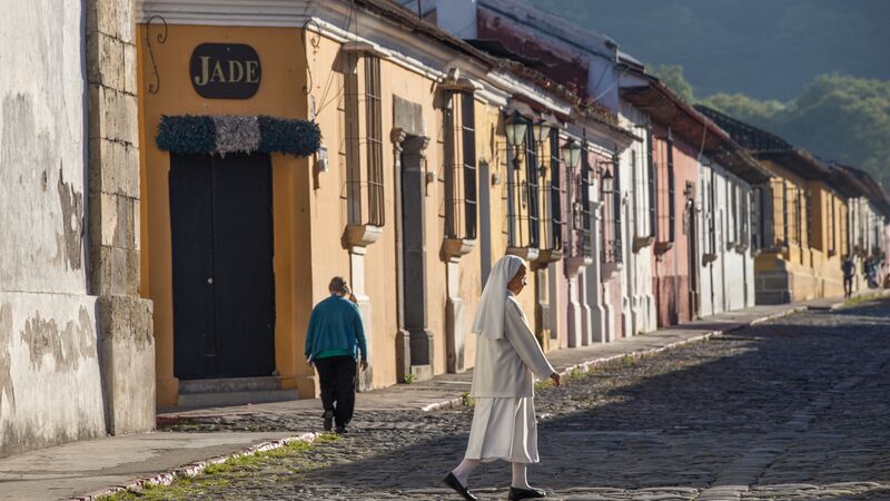 A nun walking along a cobbled street in Antigua