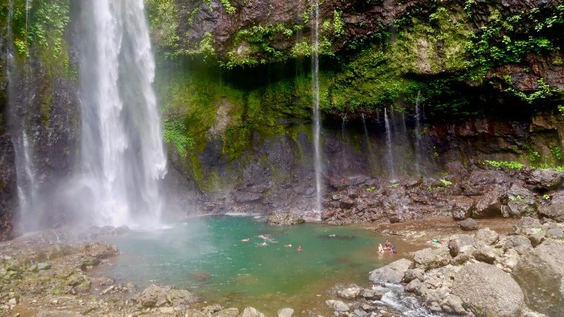 Travellers swimming in a beautiful waterfall