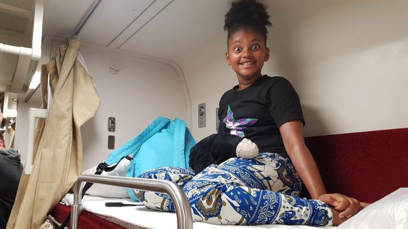 Smiling girl on a bunk on a train