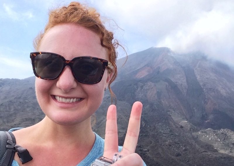 A woman takes a selfie in front of a volcano