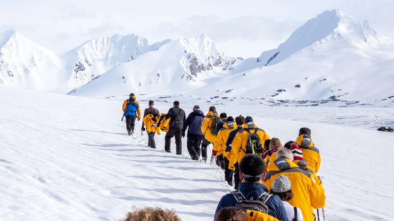 Travellers in yellow jackets walk across the ice