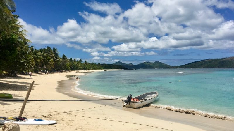 Palm trees, white sand and a calm bay in Fiji