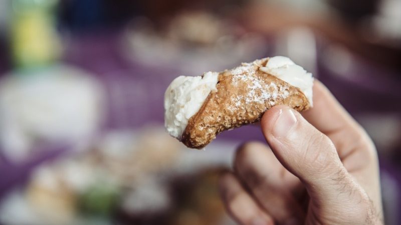 Hand holding up a cannoli