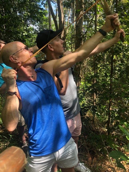 A man holds a slingshot in the jungle