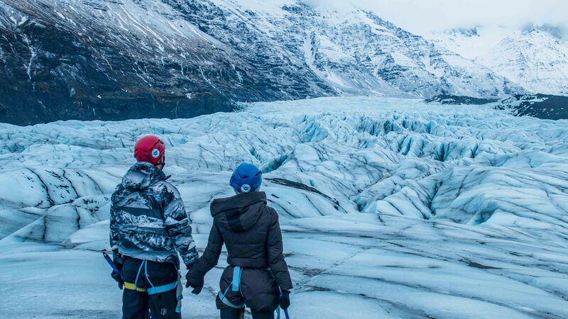 Two hikers hold hands on the ice in Iceland