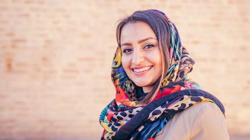 A woman wearing a hijab smiles at the camera