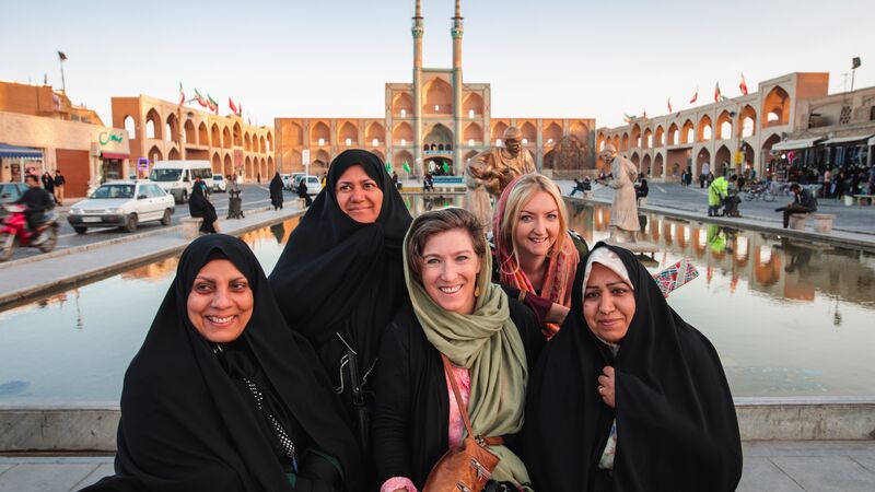 Two travellers pose for a photo with three Iranian locals