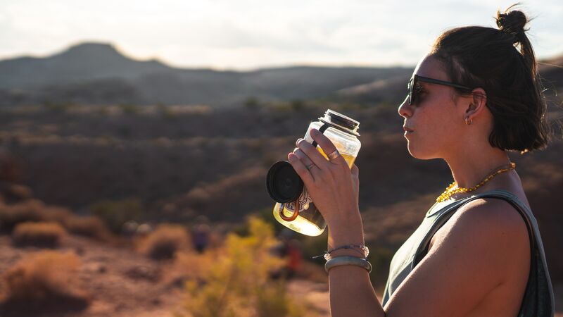 A woman drinking out of a reusable water bottle