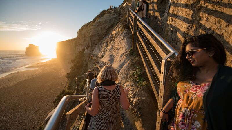 Travellers walking down a staircase to the beach in Australia