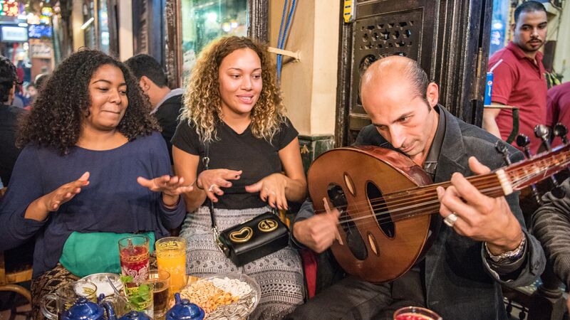 Two girls with a local musician in Cairo