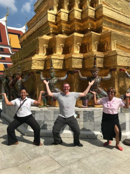 Three travellers posing in front of a gold temple