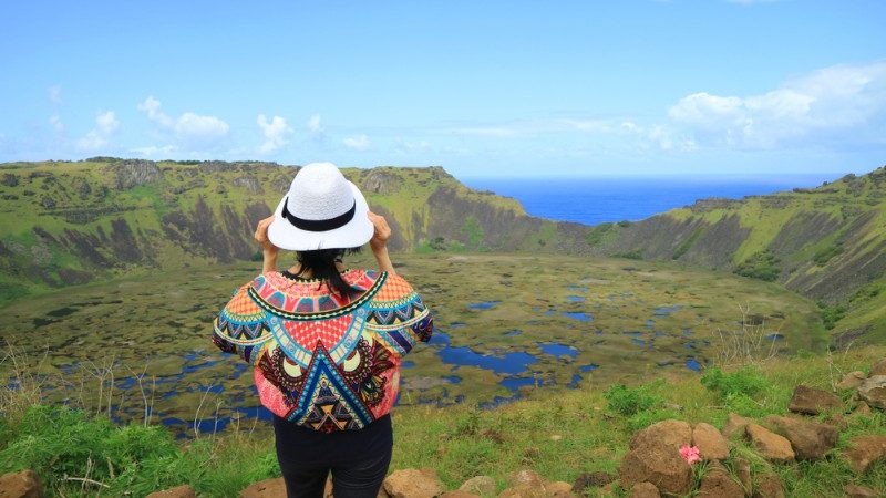 A girl wearing a colourful jumper looks out over a crater on Easter Island