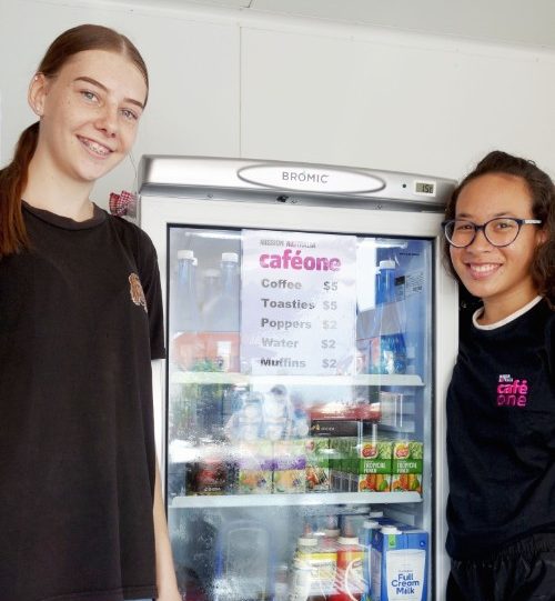 Two students standing next to a fridge