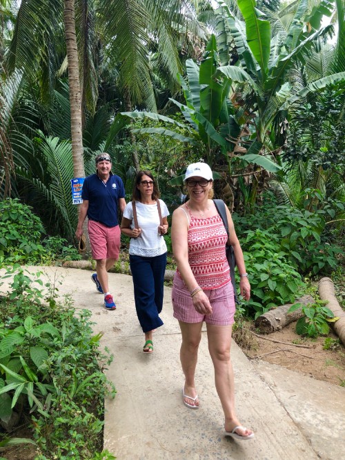 Three travellers walking through palm trees in Vietnam