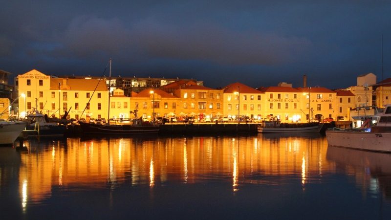 Old buildings along the waterfront in Hobart lit up at night.