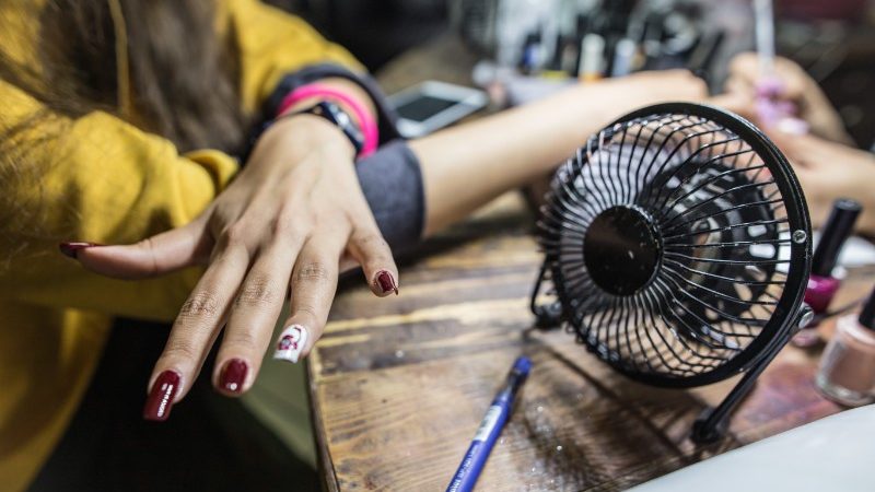 A woman dries her nails in front of a fan