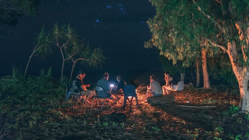 People sitting around a campfire under a starry sky