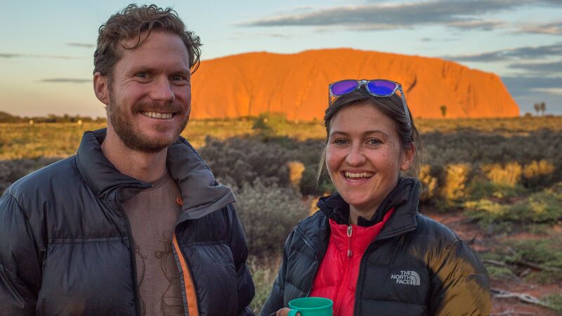 Two travellers at Uluru, smiling into the camera.