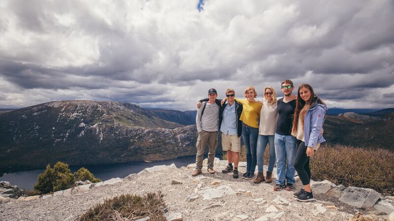 a group of travellers pose on top of a rock in Tasmania