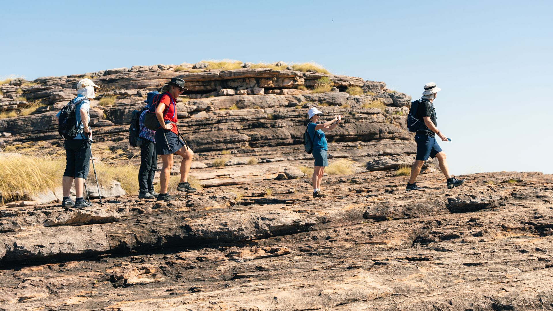 An Intrepid leader and hikers stand on top of a rocky ledge.
