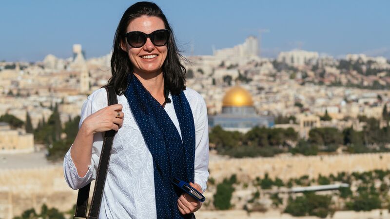 A smiling traveller in Israel with the city in the background