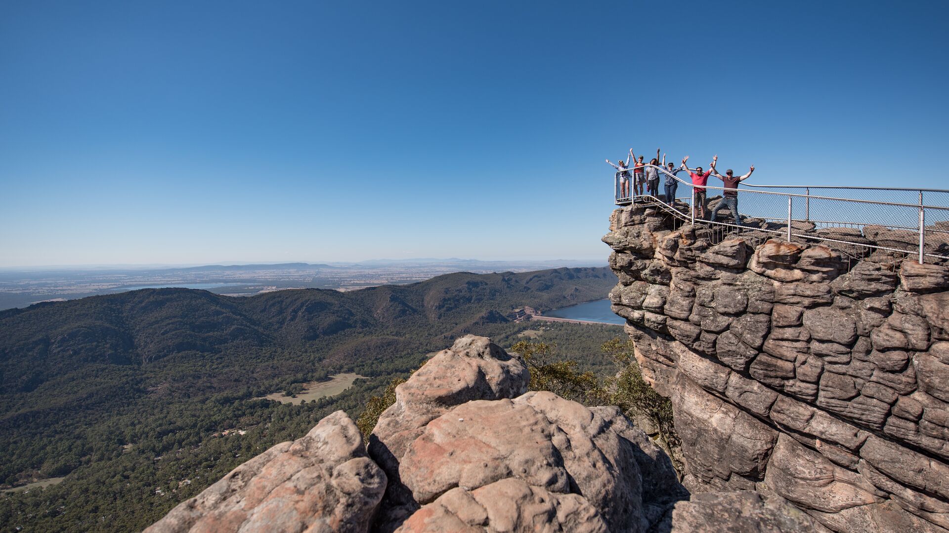 A group poses with hands in the air at the Pinnacle Lookout in the Grampians.