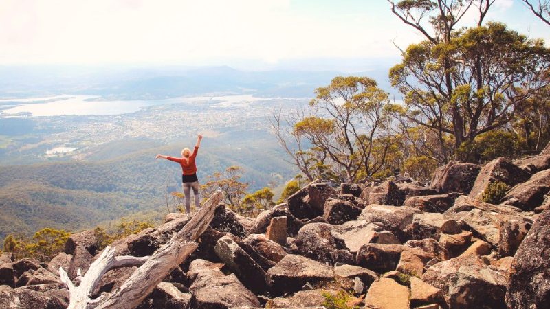 A woman standing at the top of a mountain in a national park in Tasmania