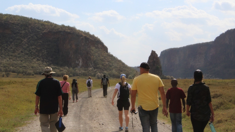 a group of men and women walking through a valley on a Kenya safari