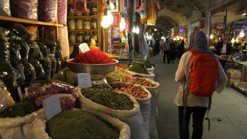 A person walking past sacks full of spices in Iran