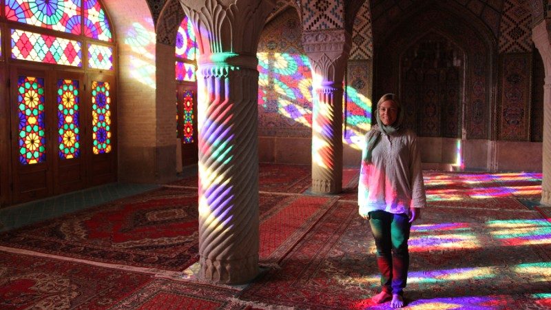 A woman standing inside a colourful mosque in Iran
