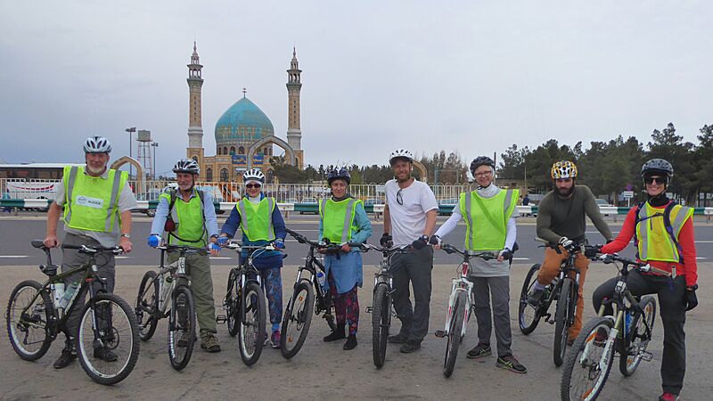 A group of cyclists in front of a mosque in Iran