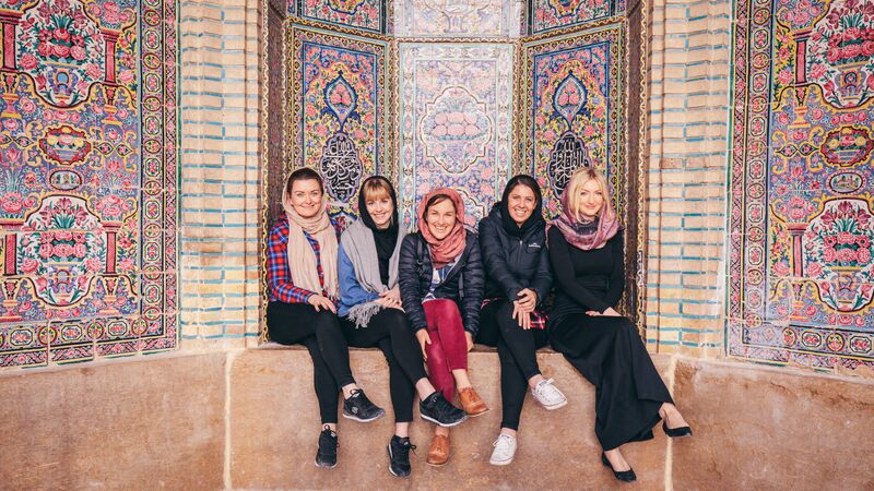 A group of smiling travellers in Iran at a mosque