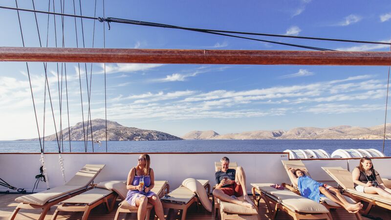 Travellers on a boat, reclining on deck chairs.