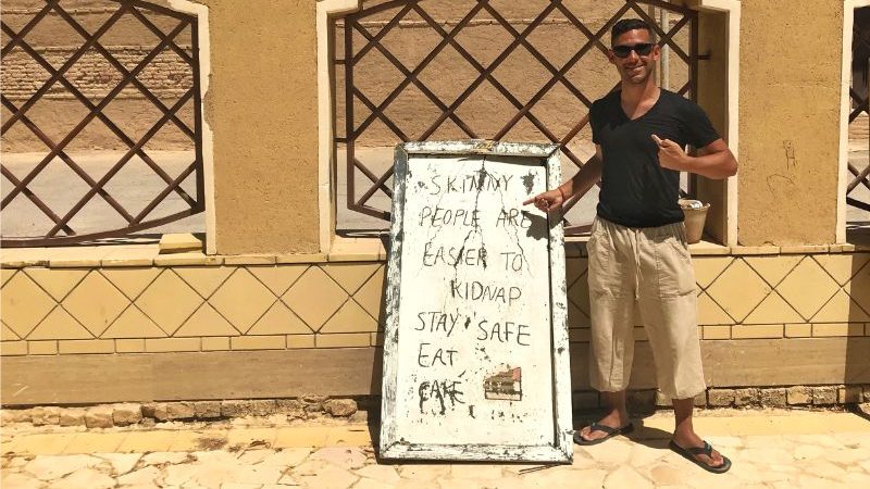 A man stands beside a sign in Iran.