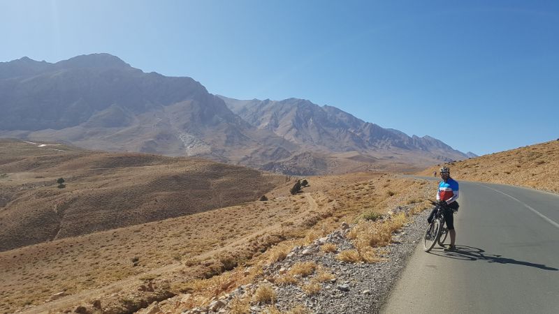 A lone cyclist standing on the side of the road in Iran