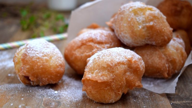 Deep fried donuts spilling out of a paper cone