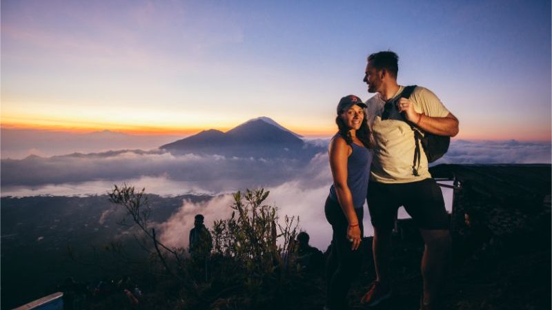 A couple standing on top of a mountain at sunrise