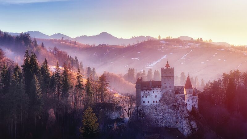 Bran or Dracula Castle in Transylvania, Romania. The castle is located on top of a mountain, sunset light