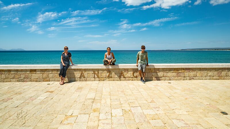 Three travellers sitting on a wall overlooking the sea in Turkey