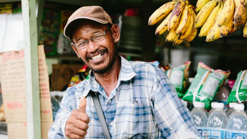 Smiling man selling bananas giving a thumbs up