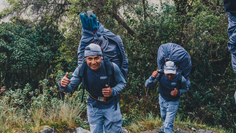 Two porters wearing backpacks giving the thumbs up