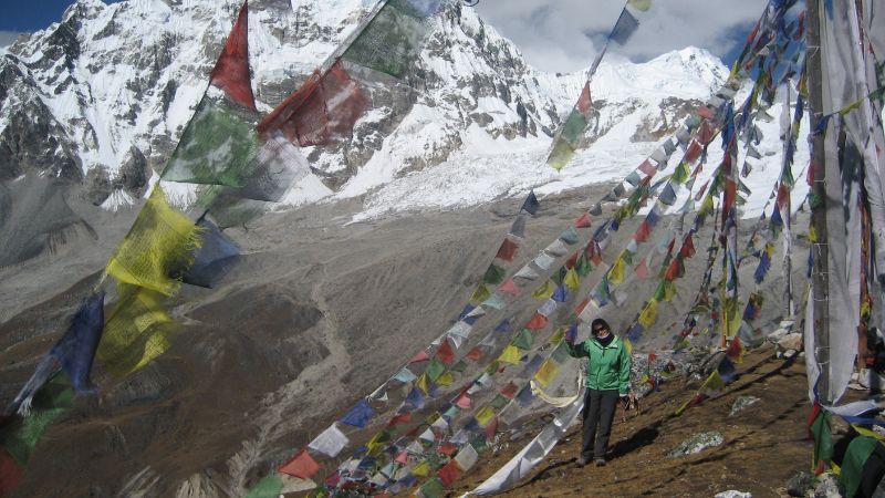 A female hiker stands under strings of flags in Nepal