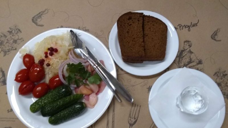 Plates filled with pickles, tomatoes, sauerkraut and dark rye bread