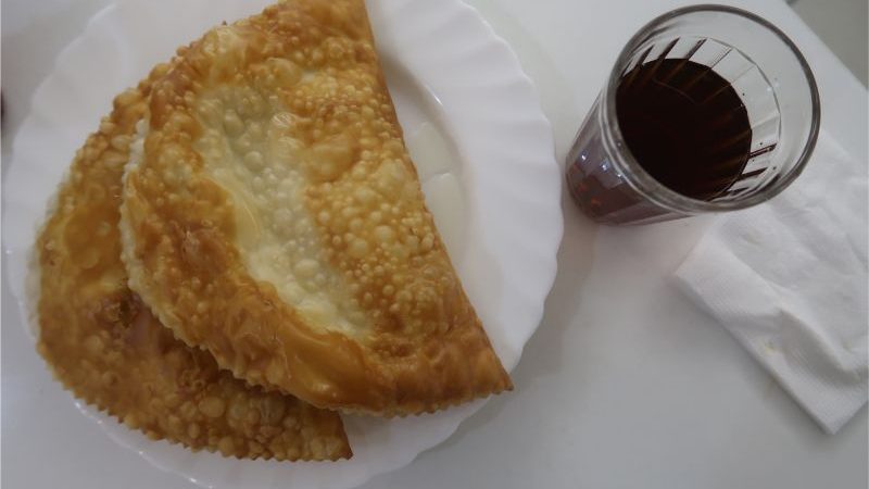 Two pastries on a white plate alongside a glass of red wine
