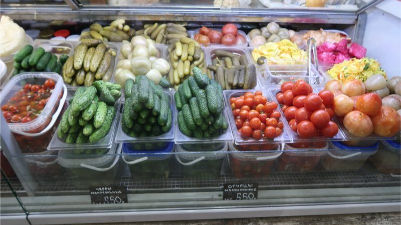 A deli counter filled with pickles and tomatoes