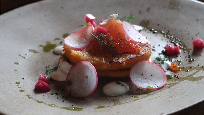 A plate of caviar and pickles on little pancakes