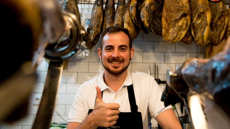 A man at a deli in Spain giving a thumbs up to the camera