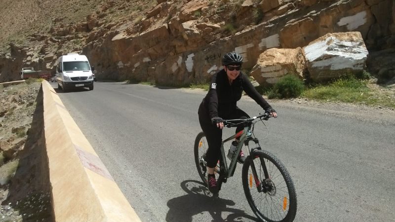 A woman cycling up a steep hill in Morocco