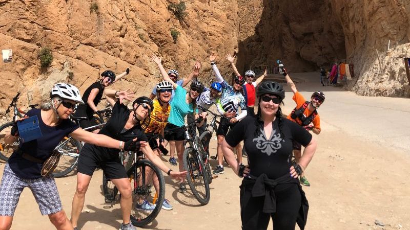 A group of cyclists standing around a smiling woman in Morocco